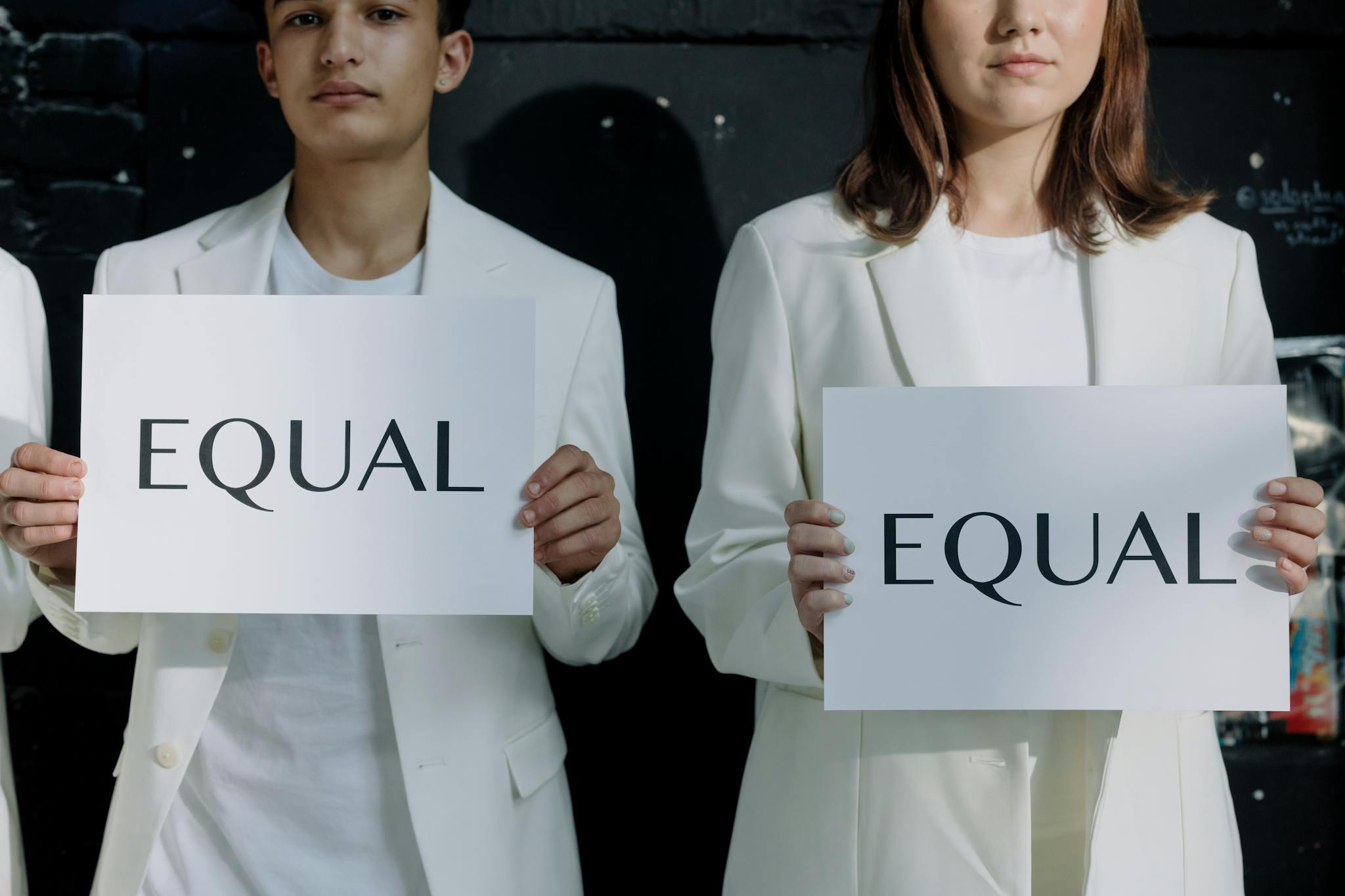 Young individuals holding 'Equal' signs promoting equality indoors.
